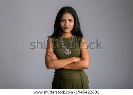 Portrait of a beautiful, smiling, emotional young woman posing with hands-folded on gray background.