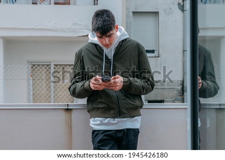 urban casual style teenager typing on mobile phone
