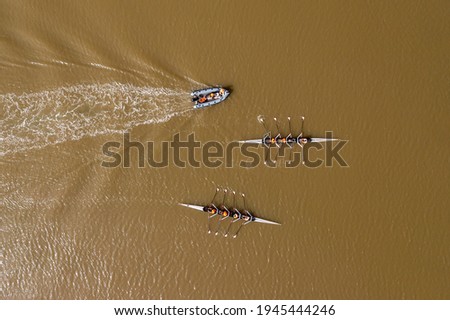 Two Sport Canoes with teams of four people racing on tranquil water, Aerial view.