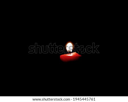 a burning red candle in the dark