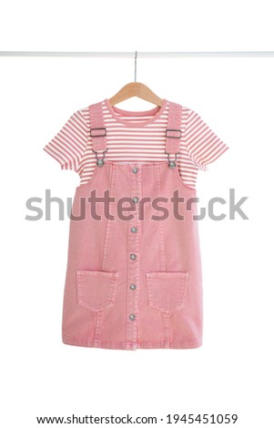 Fashionable women's kids dress and t-shirt hanging on hangers isolated on white background, girl's clothes set Royalty-Free Stock Photo #1945451059