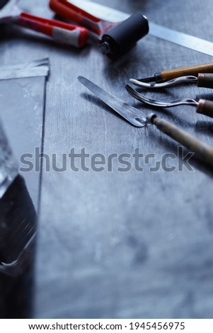 Linocut concept with copy space. Working tools in red and black colors on dark table. Cutting instruments, ink roller and other tools for linocut making. Vertical high quality photo
