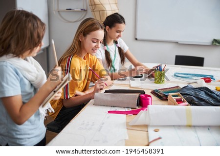 Joyful female children working in sewing workshop