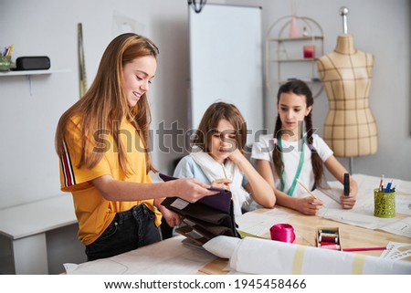 Adorable female children selecting fabrics in sewing workshop