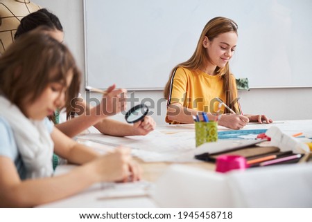 Cute children drawing clothes patterns in sewing workshop
