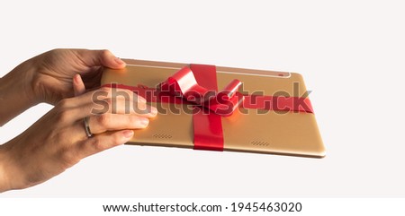 gift wrapped tablet with red bow and background ornaments