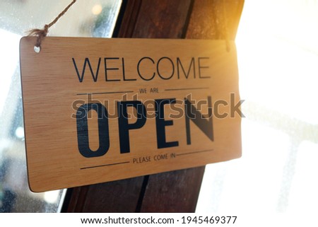 Wooden sign board that says ‘Open’ on cafe or restaurant hang on door at entrance.
