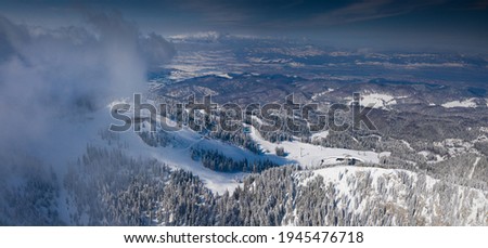 Aerial view of Poiana Brasov ski resort from Postavaru Mountains in Romania. Landmark of winter sports.