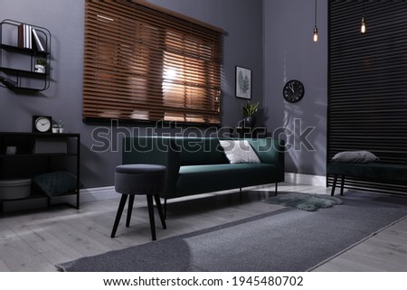 Stylish living room interior with comfortable green sofa and cushion