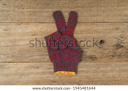 Cotton hand glove showing peace sign on shabby wooden board background.