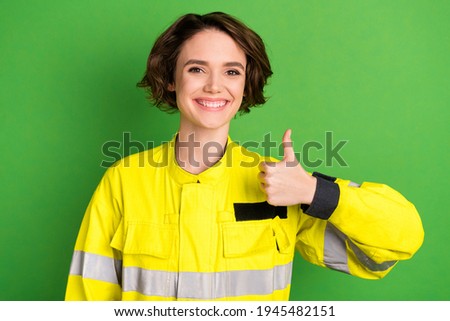 Photo of young woman firefighter happy positive smile show thumb-up like cool advert isolated over green color background