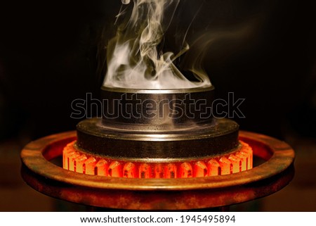 closeup calcining hot metal steel gear parts in a factory induction furnace with smoke and flame Royalty-Free Stock Photo #1945495894