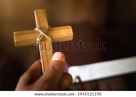 A cross in the hands of a young woman blessing on the scriptures from God with the power and power of holiness, which brings luck and the power of religion, faith, worship, Christian thought.