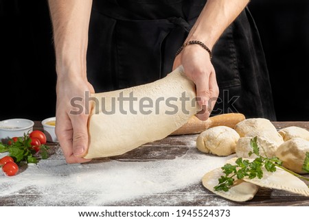 The cook prepares pasties. Step-by-step instruction. Forms the dough. Wooden background. Copy space.