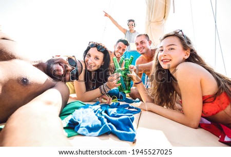 Friends group of guys and girls taking selfie at sailing boat - Luxury life style concept with young multiracial people having fun together at summer beach vacation - Bright vivid sunshine filter