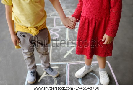 Little boy and girl on background hopscotch which drawn on asphalt.Children playing hop scotch game on playground outdoors on a sunny day. Kids having fun. Summer activities for children. Best friends
