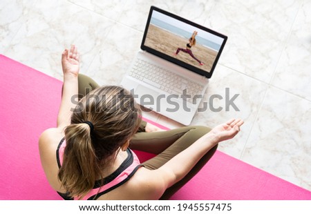 Young woman in lotus position doing yoga watching online class.Virtual yoga couch tutorial , video call education training exercises concept.Healthy lifestyle and stay fit at home.