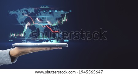 World market trading concept with digital tablet on human hand and digital financial chart graphs and world map on dark background with copyspace. Mockup Royalty-Free Stock Photo #1945565647