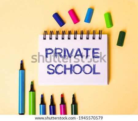 The words PRIVATE SCHOOL written in a white notebook on a beige background near multi-colored markers
