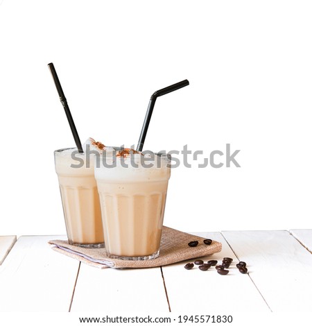 Iced or frappe coffee smoothie on glass cup and Roasted coffee beans on a white table isolated white background.