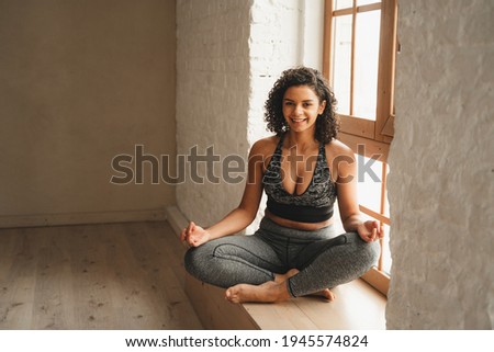 Fit athletic woman doing meditation, self control. Beautiful women working out in gym together. Intense fitness training workout in loft industrial gym