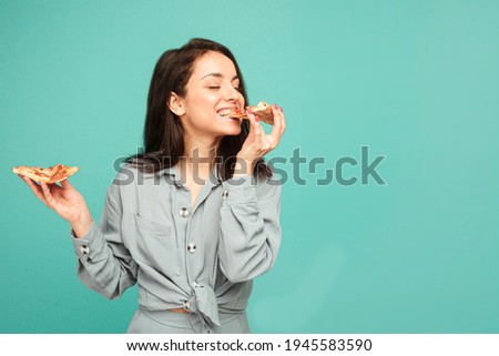 Photo of cute lady eats pizza, enjoy junk food. Wears grey shirt, isolated turquoise color background.