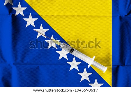 Concept of the ongoing efforts by Bosnia and Herzegowina to deliver and distribute COVID-19 Vaccine with a syringe ready to use on a Bosnian flag.
