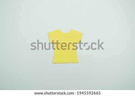 Yellow decorative piece of paper in the shape of a short-sleeved T-shirt.