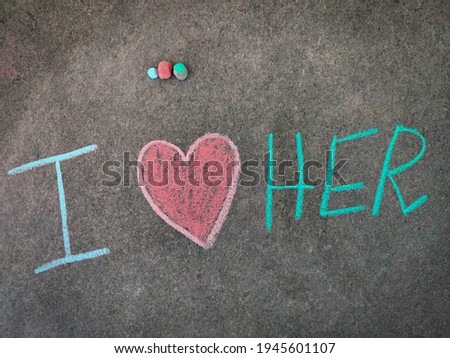The inscription text on the grey board, I with hand drawn love symbol and her . (I love her). Using color chalk pieces.