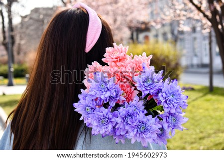 Woman with a pink bow in hair holding pink and purple flower bouquet 