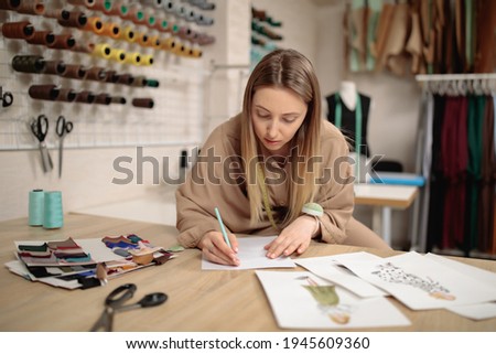 woman fashion designer draws sketches. attractive young female dressmaker or tailor sketching in studio. Small business concept