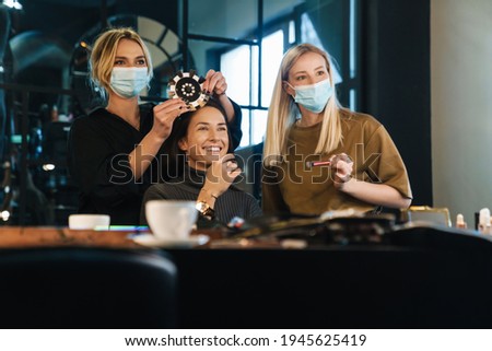 Young blonde women in face mask working with client in beauty salon