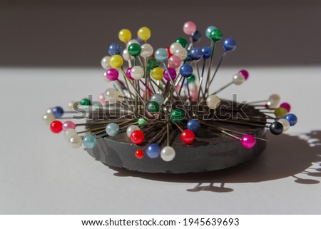 colorful pins on ring magnet white background, magnetic pin needle cushion, tailor, sewing, fashion, design materials equipments, tools, diy, cloth fastening fabric, glass headed pin Royalty-Free Stock Photo #1945639693