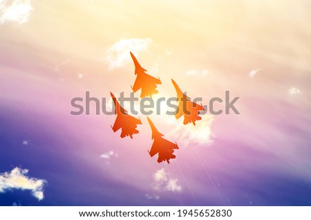 Group of fighter jet airplanes fly with the bright sun in the sky