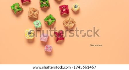 Oriental sweet dessert baklava and Turkish delight on a pastel peach colored background. Top view, flat lay. Creative layout. Banner