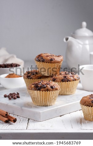 Banana muffins with chocolate chips and cinnamon, served with tea or coffee for breakfast, on white background