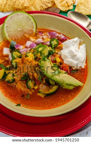 Hearty and spicy chicken tortilla soup with hot peppers and avocado garnish