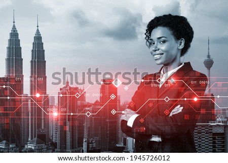 Successful smiling attractive black businesswoman pondering on technology at business process to achieve tremendous growth for client. Tech hologram icons over Kuala Lumpur background