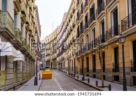 Narrow street in Madrid with typical balconies of the city and colored buildings. Spain.
