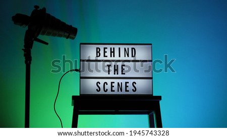 Behind the scenes letterboard text on Lightbox or Cinema Light box. Multi color LED on background. Sillhouette flash snoot hood on tripod. video production studio. Behind the scene Lightbox