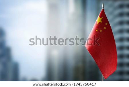 A small flag of China on the background of a blurred background