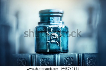 Glass poison bottle with skull and bones. Danger sign, symbol of death. Concept background on poison poisoning, pharmaceutical, chemistry, medical, old science topic. Royalty-Free Stock Photo #1945762141