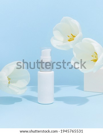 Product photography with flowers and shadows. White cosmetic tube on blue color background