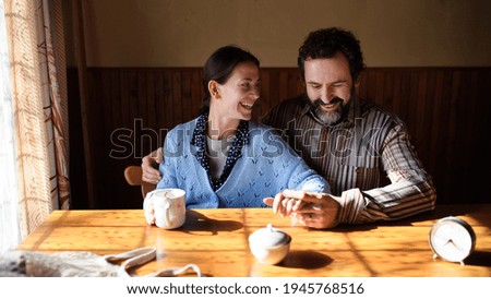Portrait of happy poor mature couple resting indoors at home, poverty concept. Royalty-Free Stock Photo #1945768516