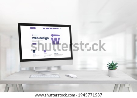 Web design studio with promo page on computer display and copy space beside Royalty-Free Stock Photo #1945771537