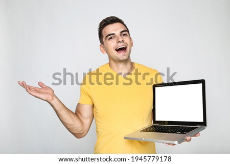 Young man with computer laptop on grey background
