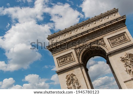 Low-angle view of majestic triumphal arch from Paris, France under slightly cloud sky. Astonishing view of white clouds in blue skyline above sublime European monument. French landmarks