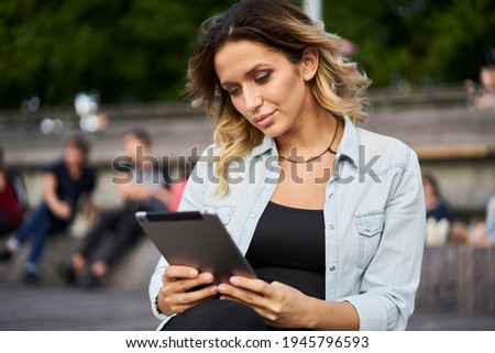 Caucasian hipster girl in casual wear browsing web page on modern touch pad technology using 4g wireless outdoors, young female blogger connecting to internet for networking social media on leisure