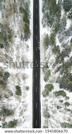 Aerial shot of snow covered road. Snowy forrest with captured from above with a drone.