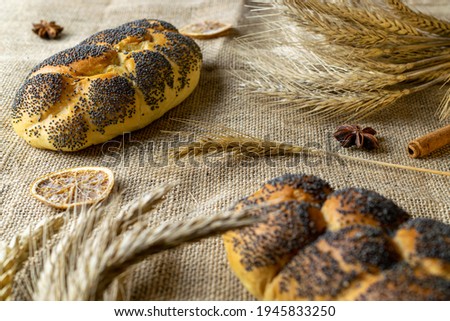 Whole wheat bread. Fresh loaf of rustic traditional bread with poppy seeds, wheat grain ear on linen texture background. Rye bakery with crusty loaves and crumbs. Homemade baking